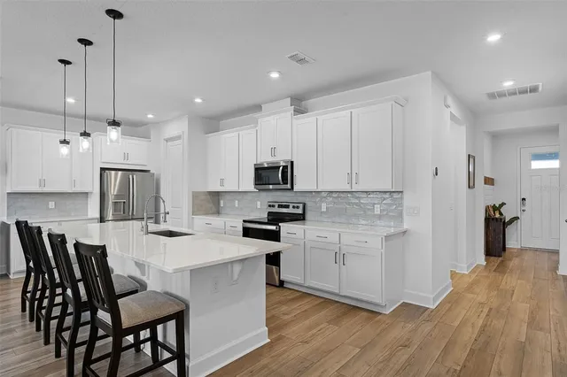 a kitchen with stainless steel appliances kitchen island granite countertop a table chairs microwave and sink