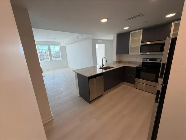 a kitchen with stainless steel appliances kitchen island granite countertop a stove refrigerator and sink