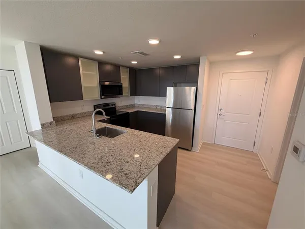 a kitchen with stainless steel appliances granite countertop a sink a refrigerator and a sink