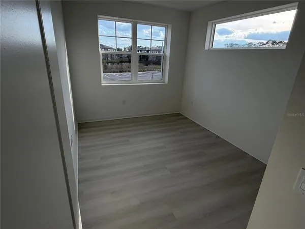 an empty room with wooden floor and windows