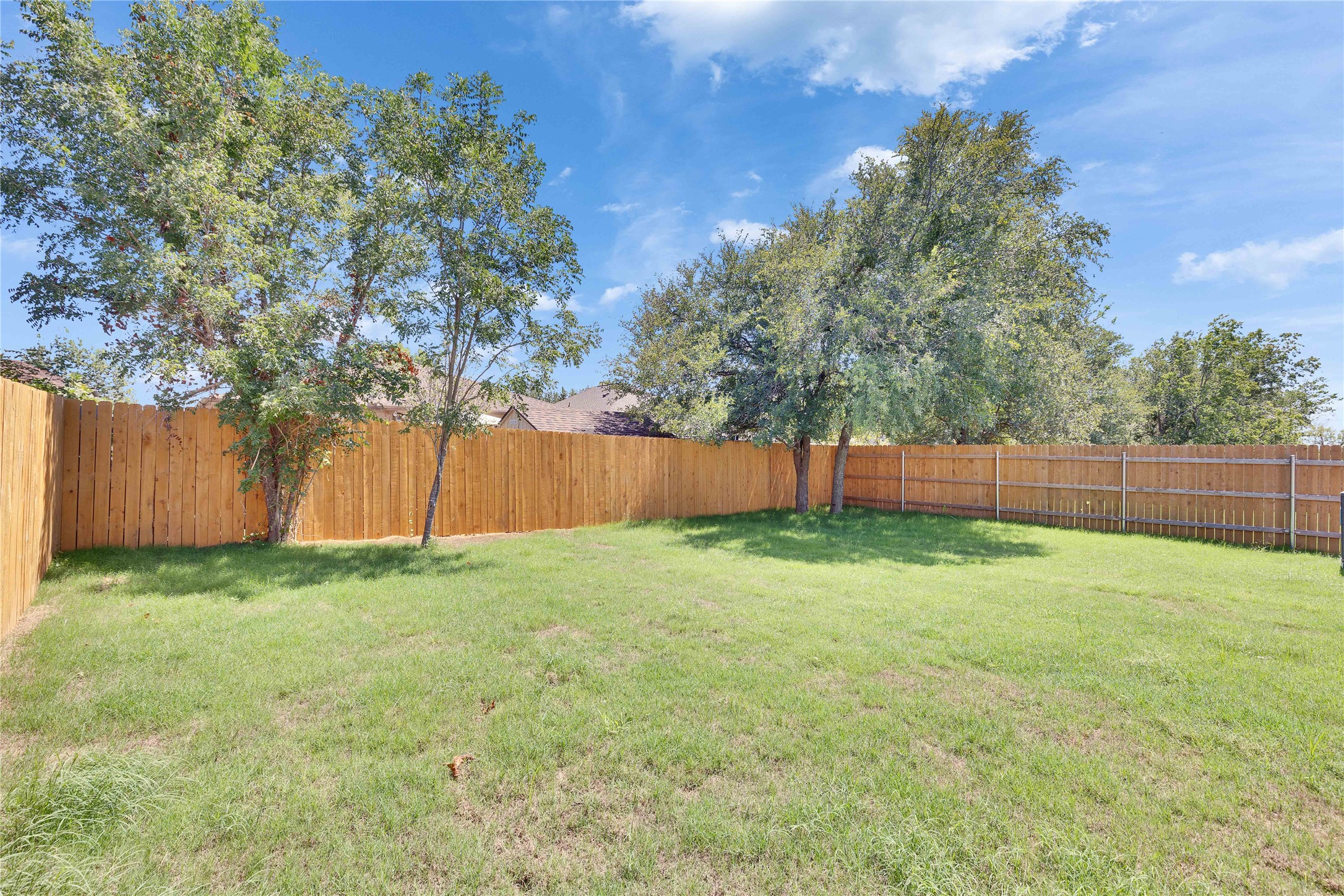 13509 Barn Chime Street Elgin, TX 78621 - Photo 32 of 40 Spacious backyard featuring a full wood privacy fence, a manicured lawn, and mature trees providing natural shade