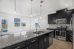 a kitchen with stainless steel appliances granite countertop a sink a stove and a wooden floors