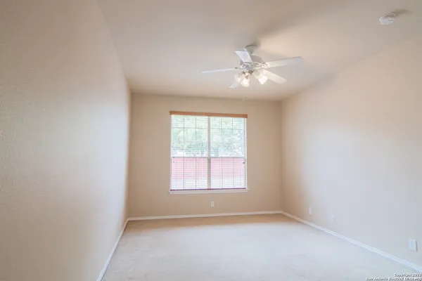 an empty room with chandelier fan and windows