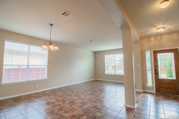 a view of an empty room with window and chandelier fan