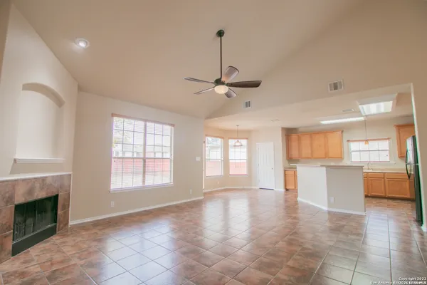 a view of an empty room with a kitchen and a fireplace