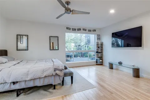 a bedroom with a bed a flat screen tv and a large window