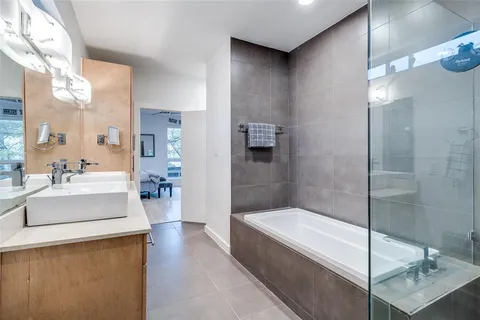 a bathroom with a tub a mirror and a shower