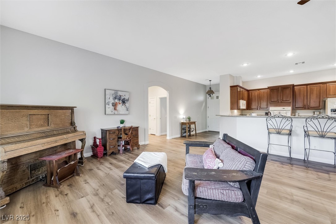 10720 Elm Ridge Avenue Las Vegas, NV 89144 - Photo 16 of 67 Living room featuring arched walkways, light wood-type flooring, and recessed lighting