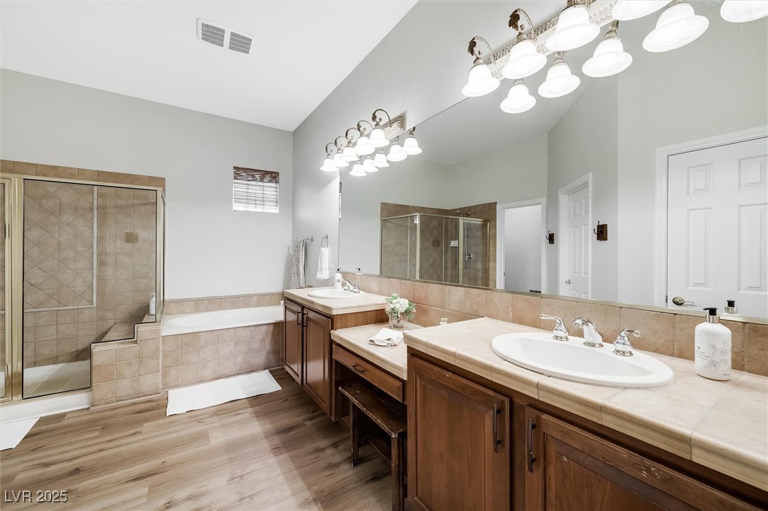 10720 Elm Ridge Avenue Las Vegas, NV 89144 - Photo 35 of 67 Bathroom featuring double vanity, a shower stall, a garden tub, and light wood-style floors