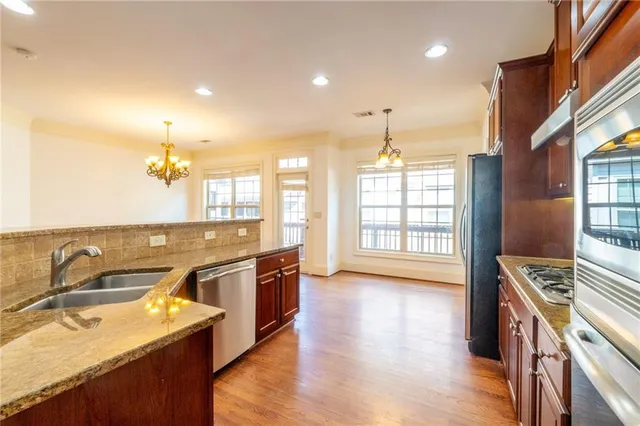 a kitchen with stainless steel appliances granite countertop a sink stove and wooden floor