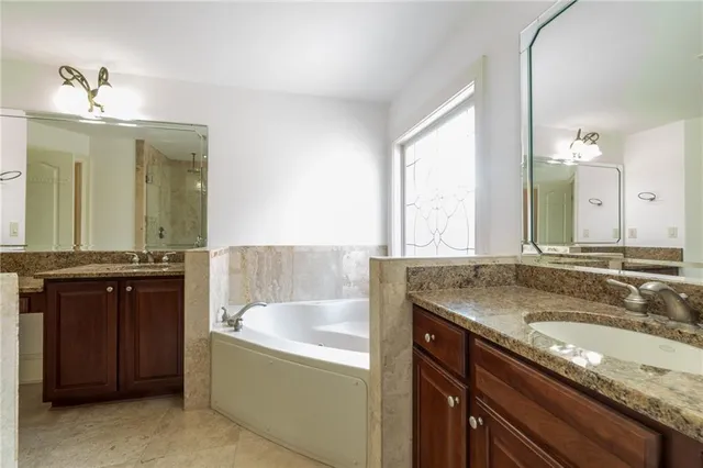 a bathroom with a granite countertop sink a large mirror and a bathtub