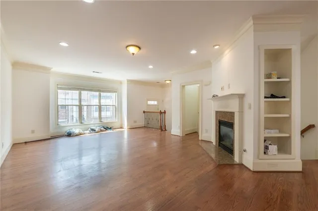 a view of an empty room with wooden floor and a fireplace