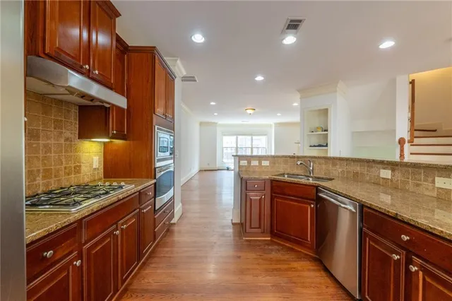 a kitchen with stainless steel appliances granite countertop a stove a sink and a refrigerator