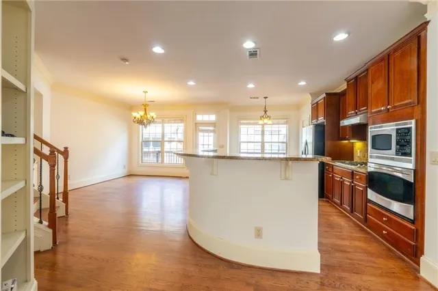 a view of kitchen with stainless steel appliances granite countertop a stove top oven a sink and a refrigerator