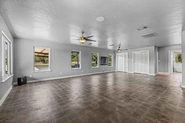 an empty room with windows and ceiling fan