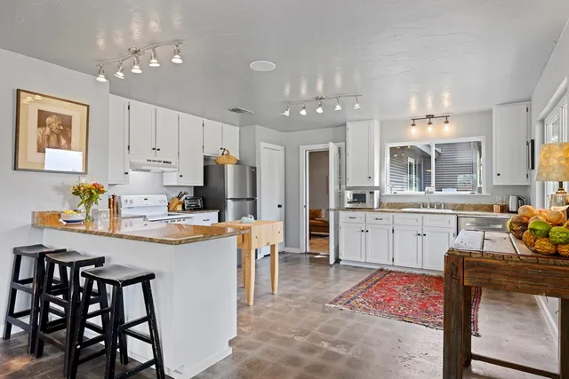 a kitchen with kitchen island granite countertop a sink cabinets and stainless steel appliances