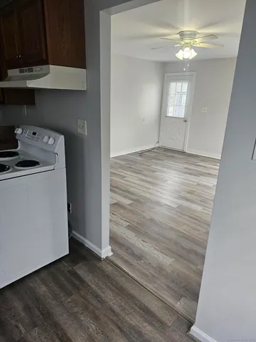 a view of empty room with wooden floor and fan