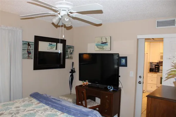 a bedroom with a flat screen tv and a ceiling fan