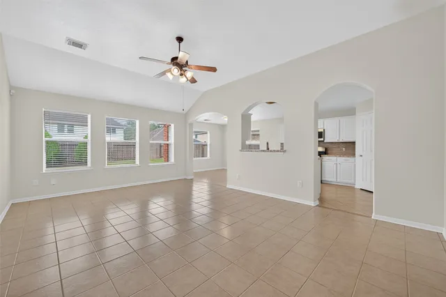 a view of an empty room with a window and kitchen view