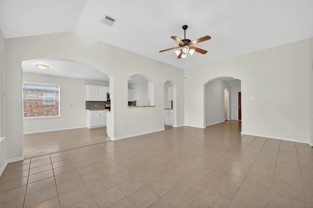 a view of an empty room with a ceiling fan and window