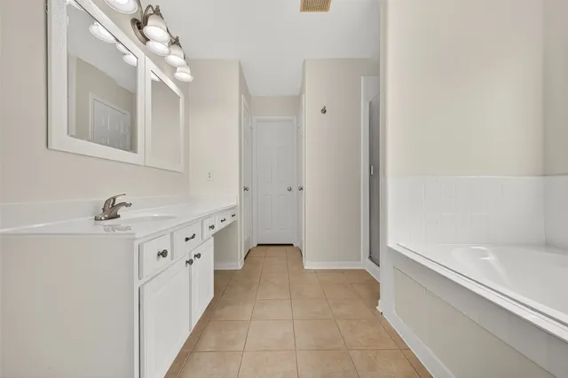 a spacious bathroom with a bathtub sink and mirror
