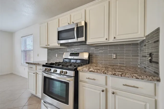 a kitchen with stainless steel appliances granite countertop grey cabinets a stove a sink and dishwasher