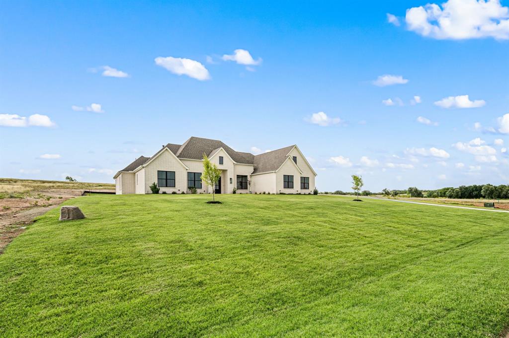 3006 Wheeler Branch Road Granbury, TX 76049 - Photo 2 of 29 Single-story residence featuring a light-colored brick exterior, dark-framed windows, a multi-gabled roofline, and an expansive manicured lawn