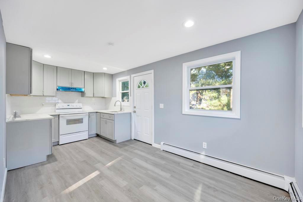 231 Elm Road West Mastic Beach, NY 11951 - Photo 19 of 34 a kitchen with white cabinets and white appliances