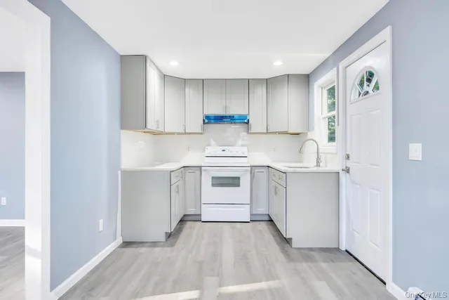 a kitchen with a white stove top oven and white kitchen