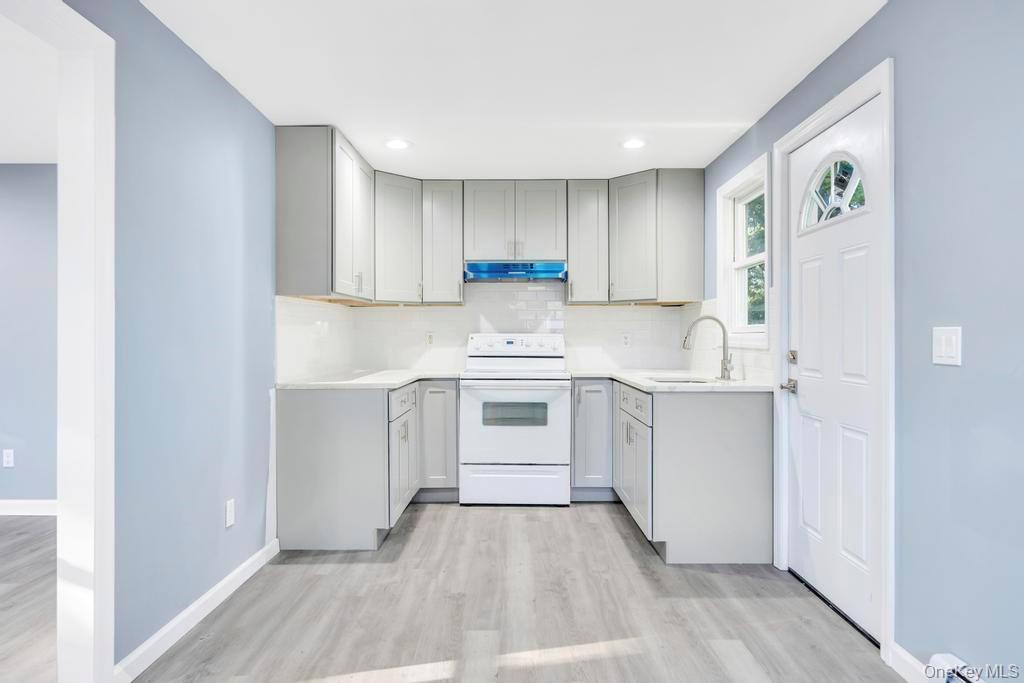 231 Elm Road West Mastic Beach, NY 11951 - Photo 21 of 34 a kitchen with a white stove top oven and white kitchen