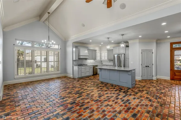 a large white kitchen with kitchen island a sink stainless steel appliances and cabinets