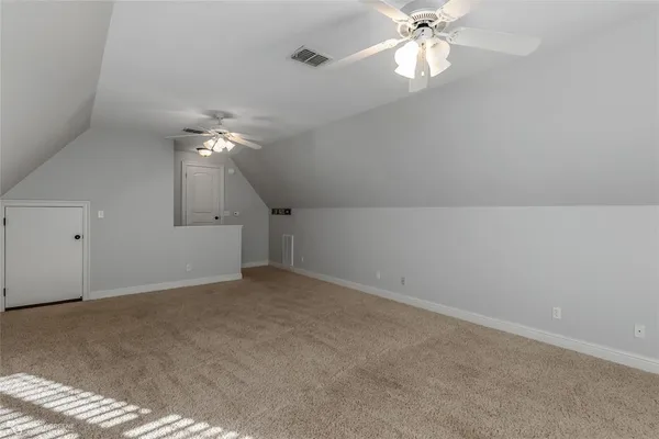 an empty room with a chandelier fan and windows