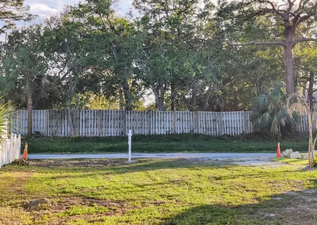 a view of swimming pool with wooden fence and trees in the background