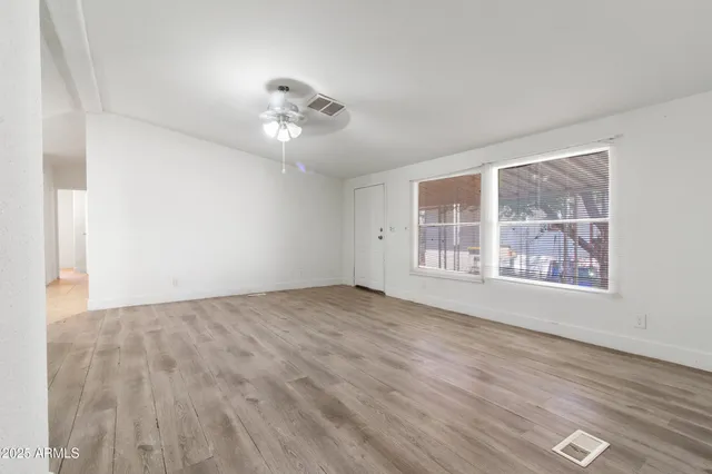 an empty room with wooden floor and windows