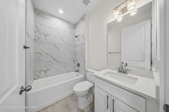 a bathroom with a granite countertop sink a toilet and shower