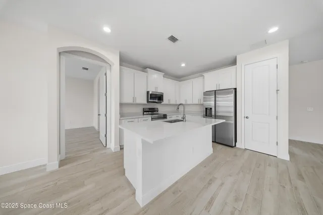 a kitchen with stainless steel appliances a refrigerator sink and cabinets