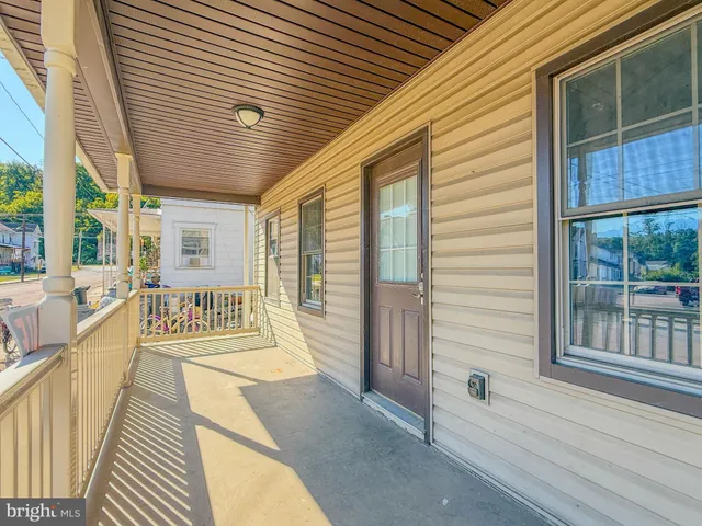 a view of a room with wooden floor a ceiling fan and windows