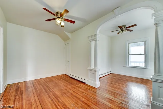 an empty room with wooden floor and ceiling fan