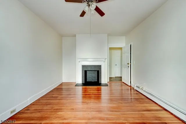 a view of a livingroom with wooden floor a fireplace and window