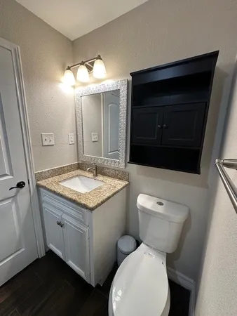 a bathroom with a granite countertop toilet sink and mirror