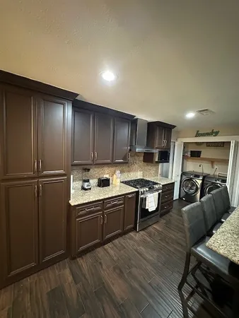 a kitchen with stainless steel appliances granite countertop a refrigerator a sink dishwasher a stove and a microwave oven with wooden floor