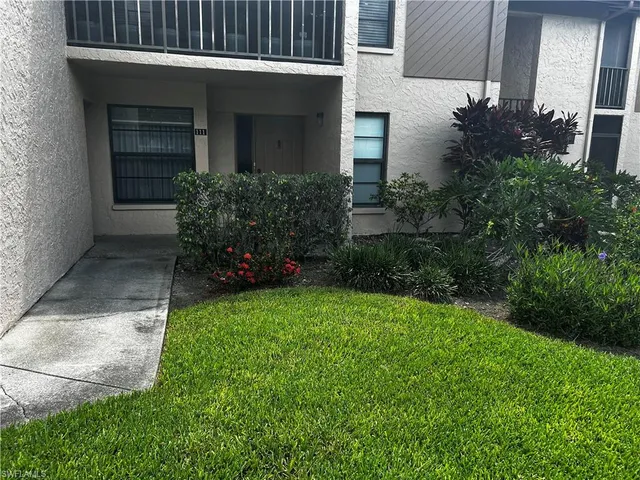 a view of a house with brick walls and a yard with plants