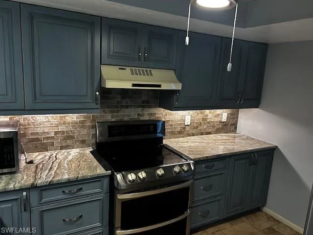 a kitchen with granite countertop a stove and a microwave