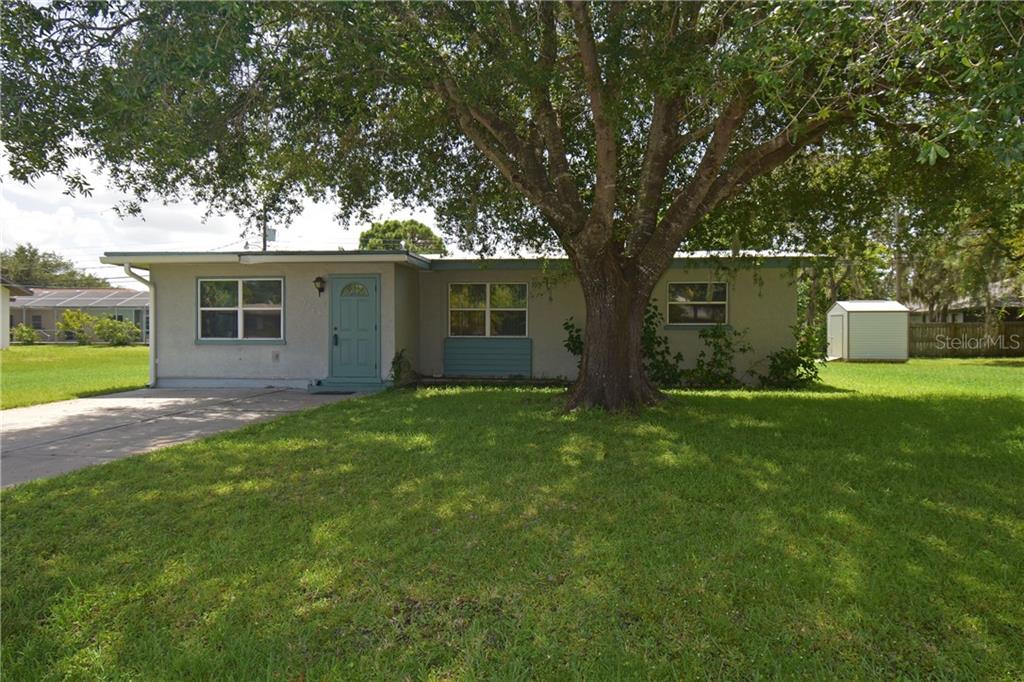 1065 Hudson Road Venice, FL 34293 - Photo 1 of 1 Front of the house features a shady large driveway and a nice green lawn with a new garden shed.