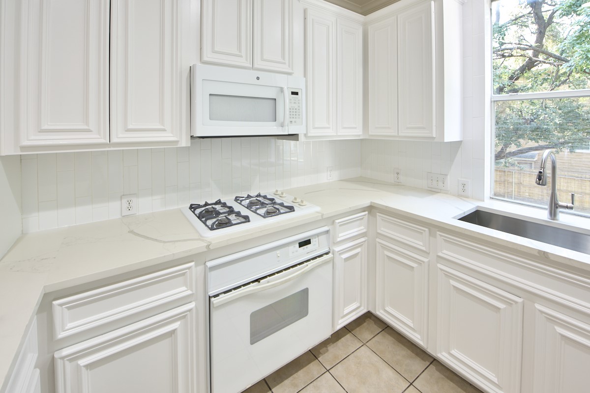 918 Cohn Street Houston, TX 77007 - Photo 3 of 32 a kitchen with white cabinets and white appliances