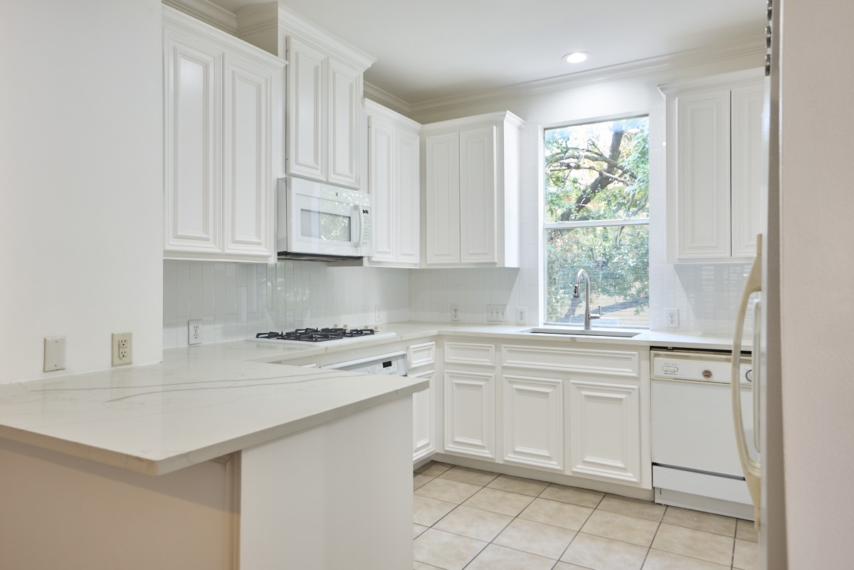 918 Cohn Street Houston, TX 77007 - Photo 9 of 32 a kitchen with white cabinets and white appliances