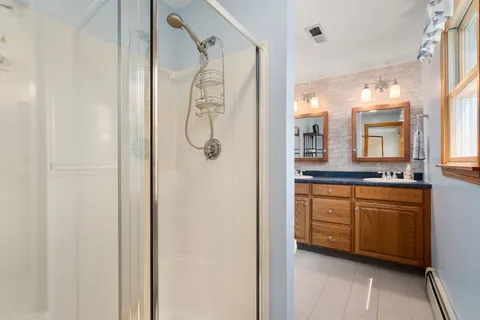 a bathroom with a double vanity sink mirror and shower