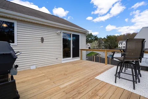 a view of a patio with table and chairs with wooden floor and fence