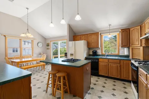 a kitchen with stainless steel appliances granite countertop a stove a sink a refrigerator and a dining table with wooden floor