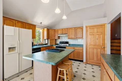 a kitchen with a refrigerator a stove a sink dishwasher and wooden cabinets with wooden floor